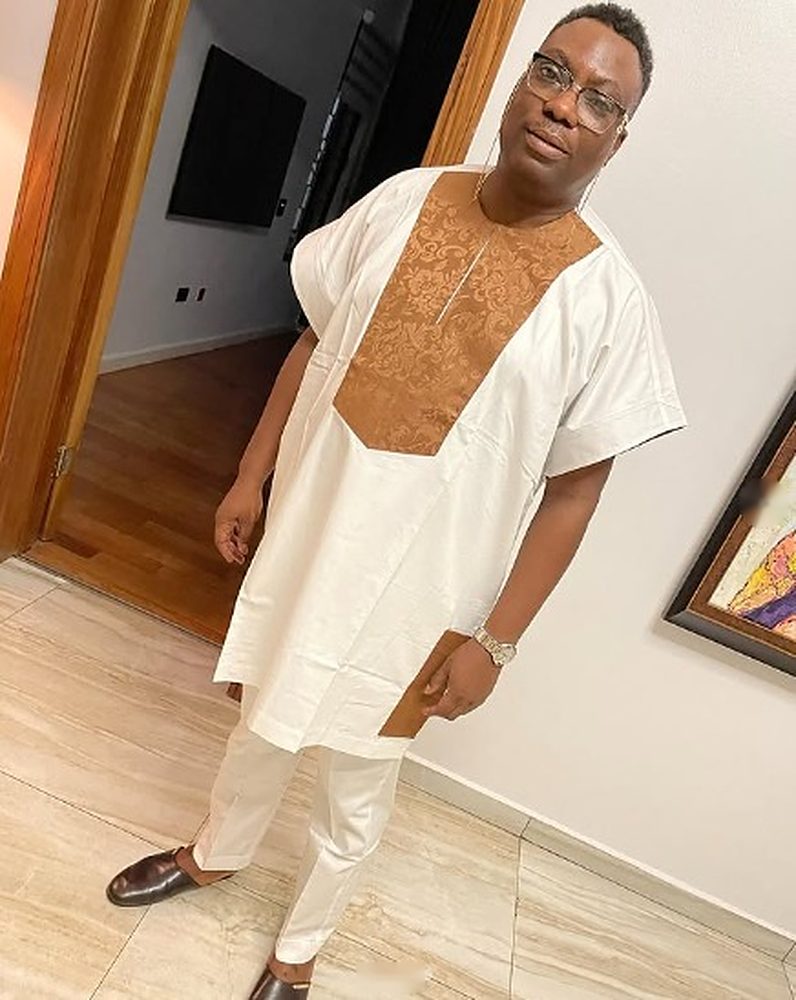 Man in a white short-sleeve senator with a copper damask brocade bib panel and white trousers