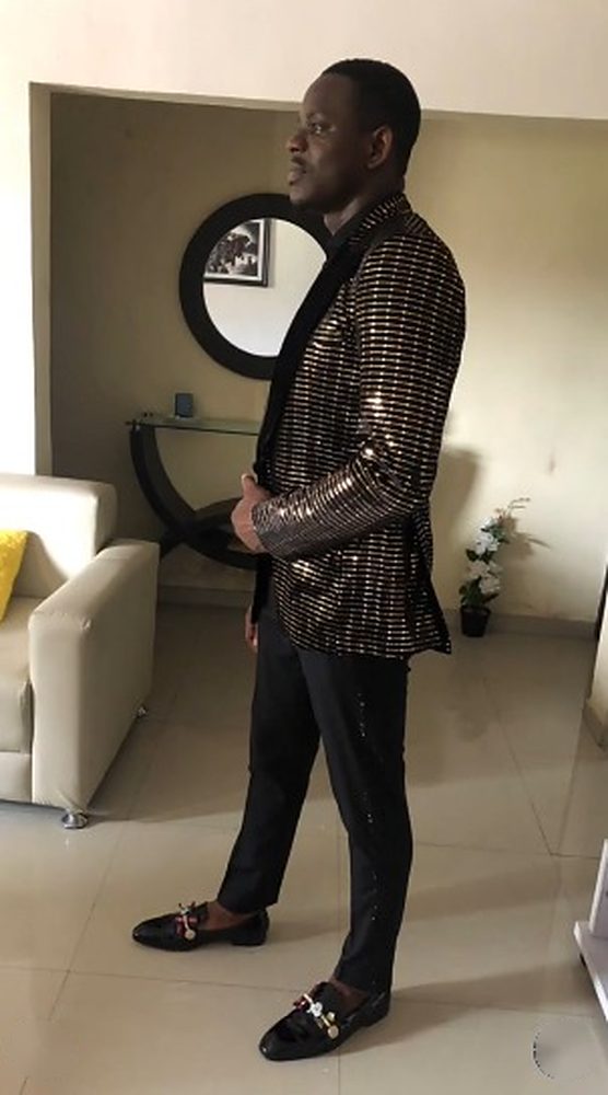 Side view of a man in a black jacket with gold sequin stripes and a black velvet shawl collar
