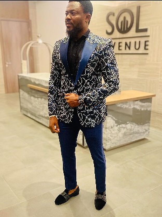 Man in a black dinner jacket with white etched-line jacquard pattern and navy satin peak lapels