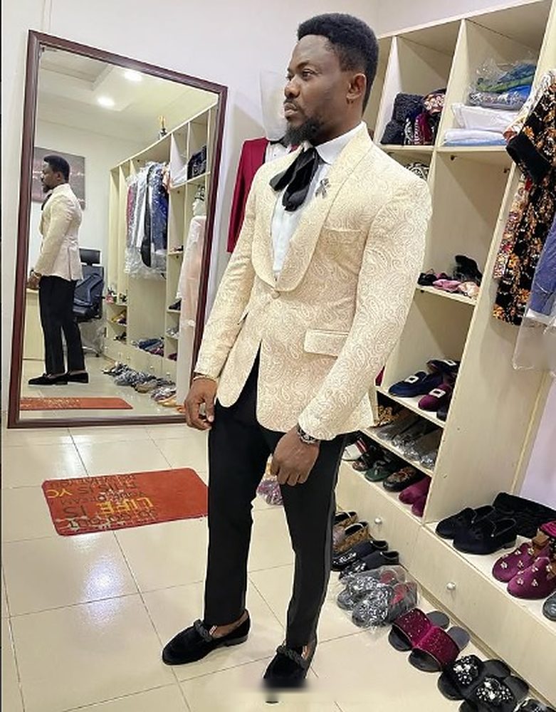 Man in an ivory paisley jacquard shawl-lapel tuxedo jacket with black trousers and velvet loafers